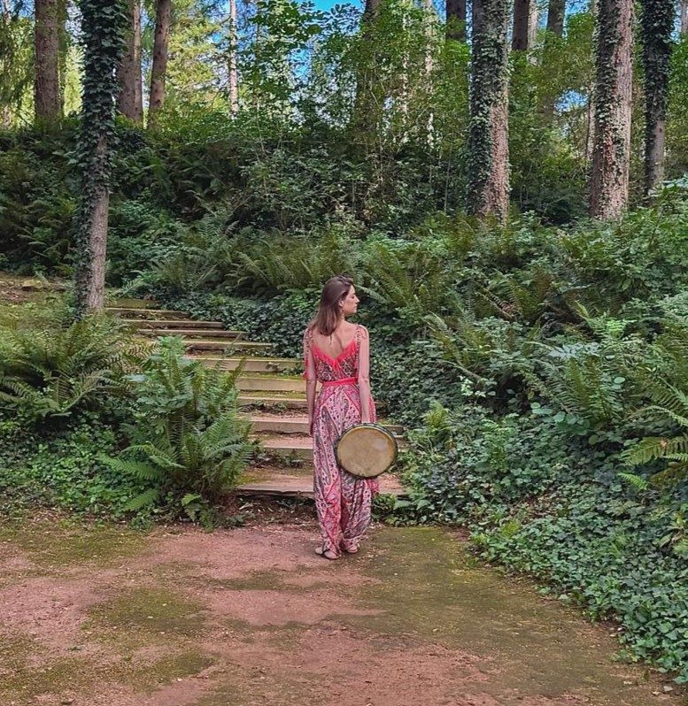 Estefanía con el tambor en un bosque, junto a una escalera de madera